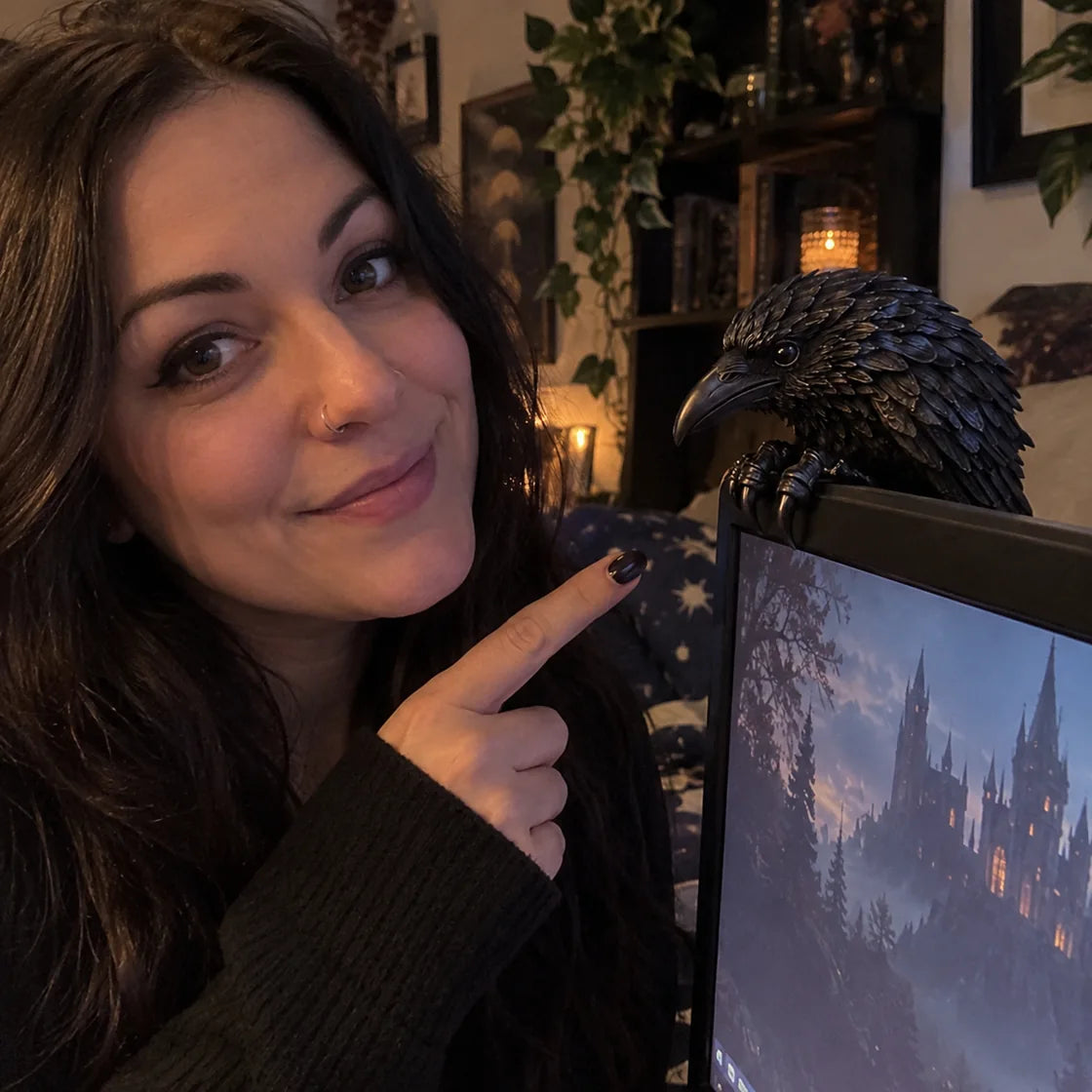 Person displaying a raven figurine beside a monitor