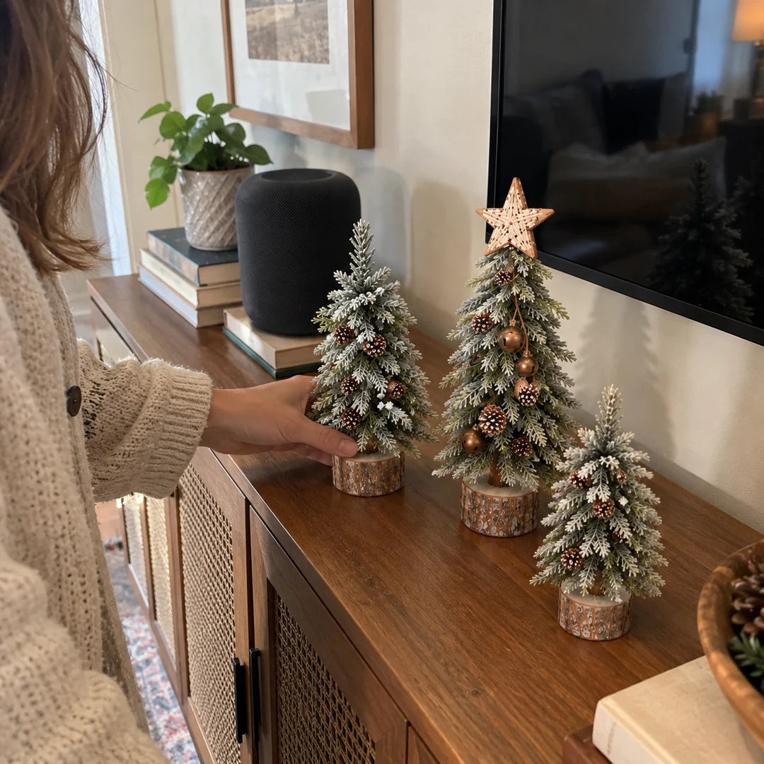 Woman arranging miniature Christmas trees on a living room console