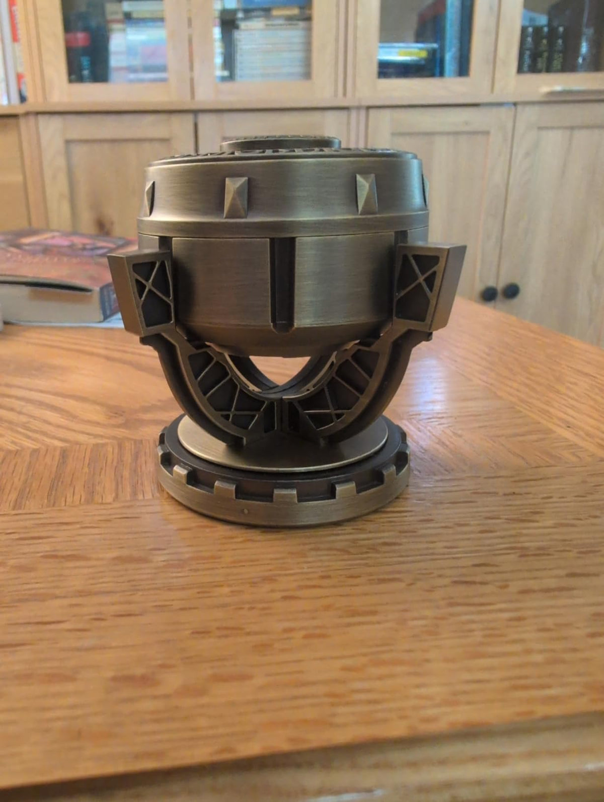 Real photo showing the bronze-tone dice vault on a wooden tabletop